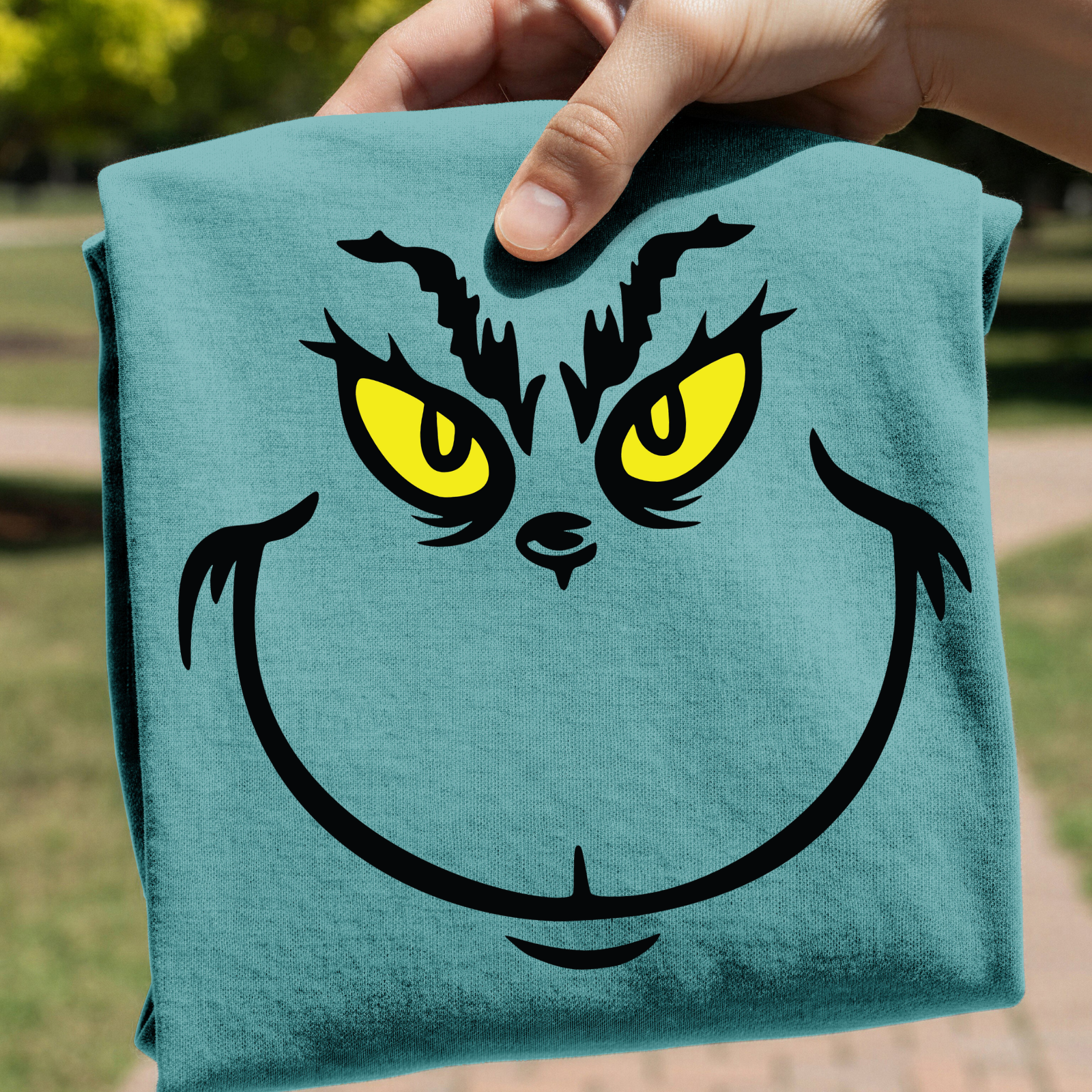 Teal towel with Grinch face design held by a hand outdoors