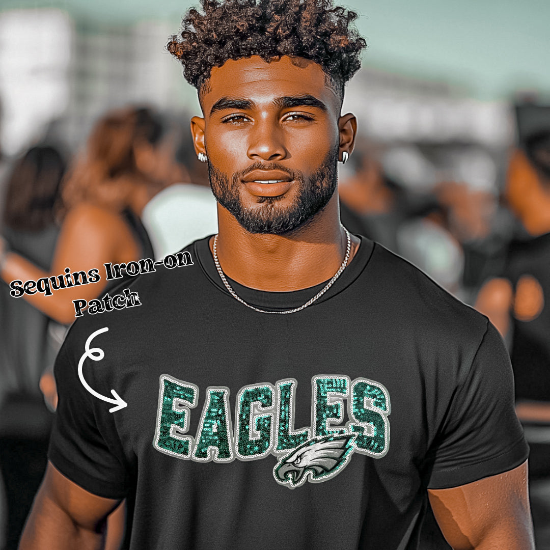 A man wearing a black T-shirt with an Eagles sequins iron-on patch on the front.