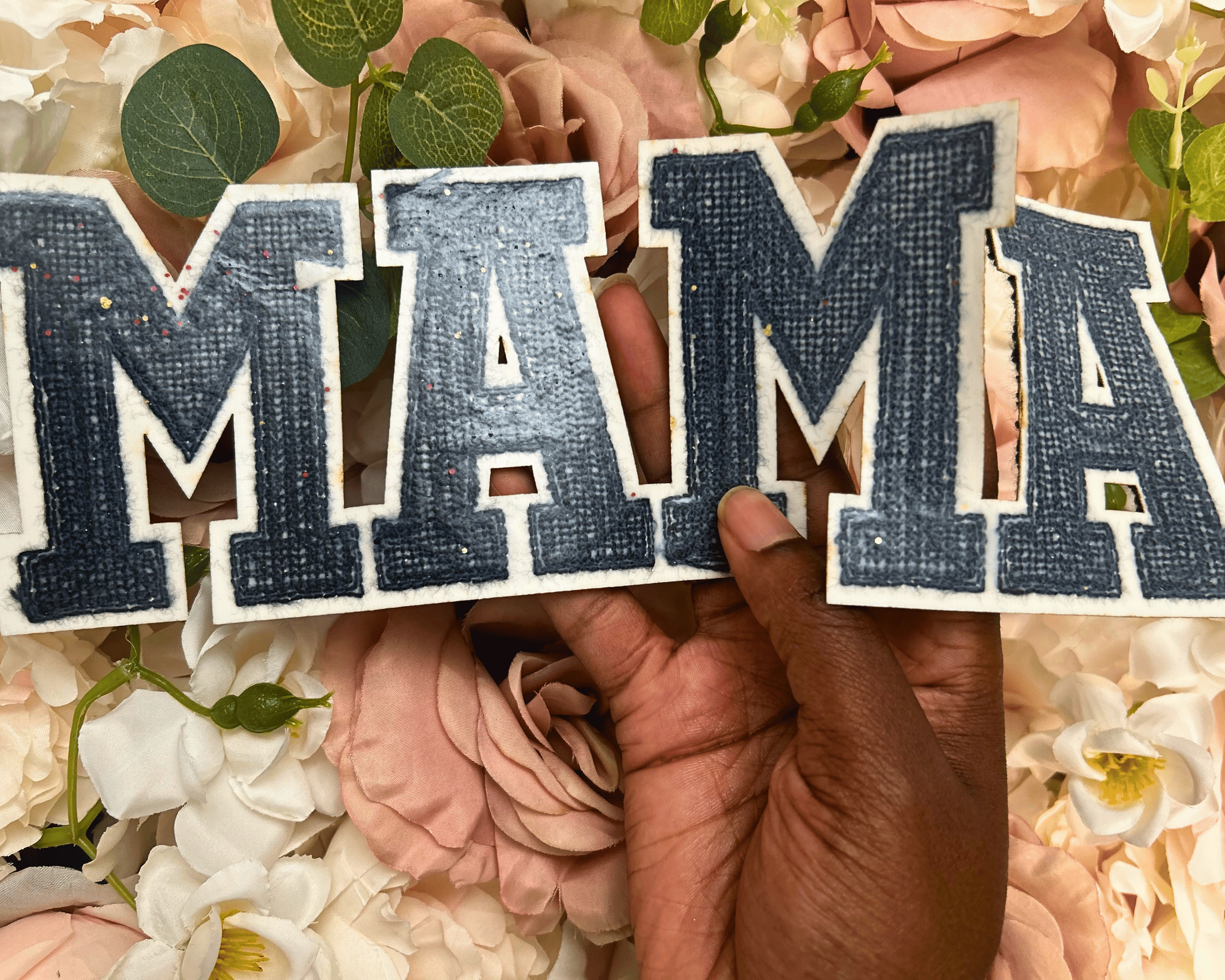 Hand holding wooden letters spelling &