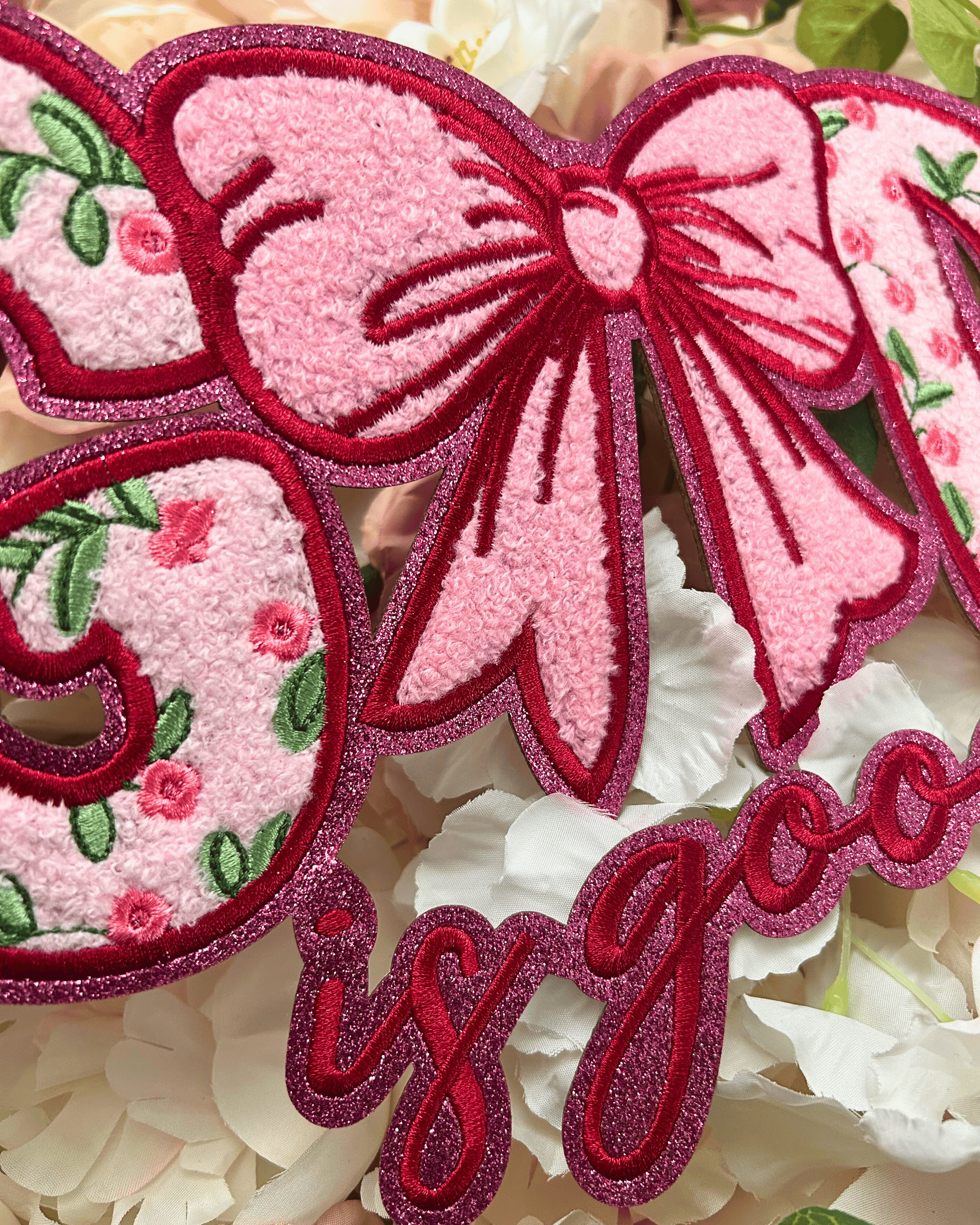 Decorative patch with pink and red bow and floral design on a textured background