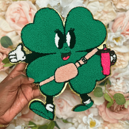 Green cartoon character patch held over a floral background