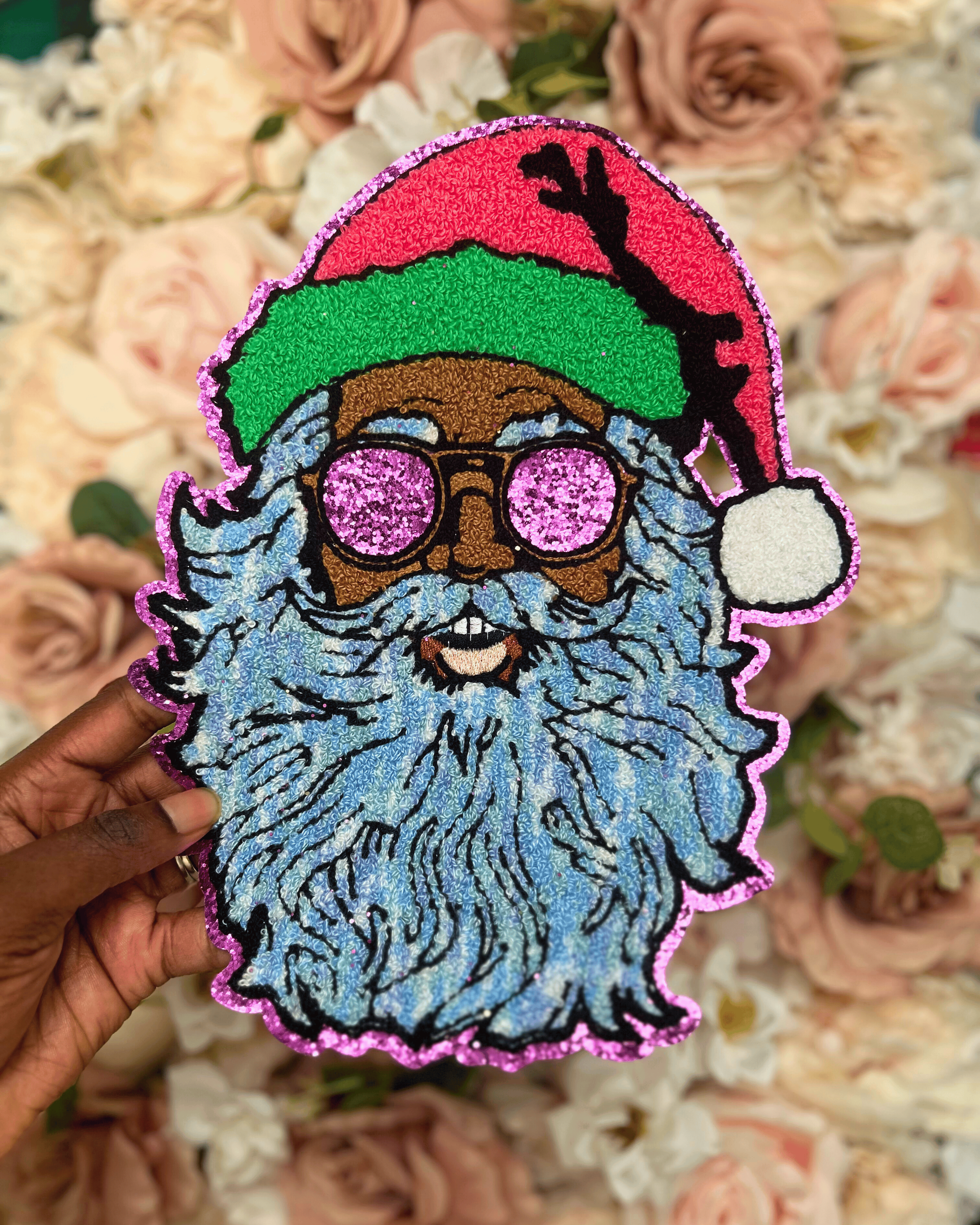Colorful patch of a bearded figure with glasses and a red hat held over a floral background