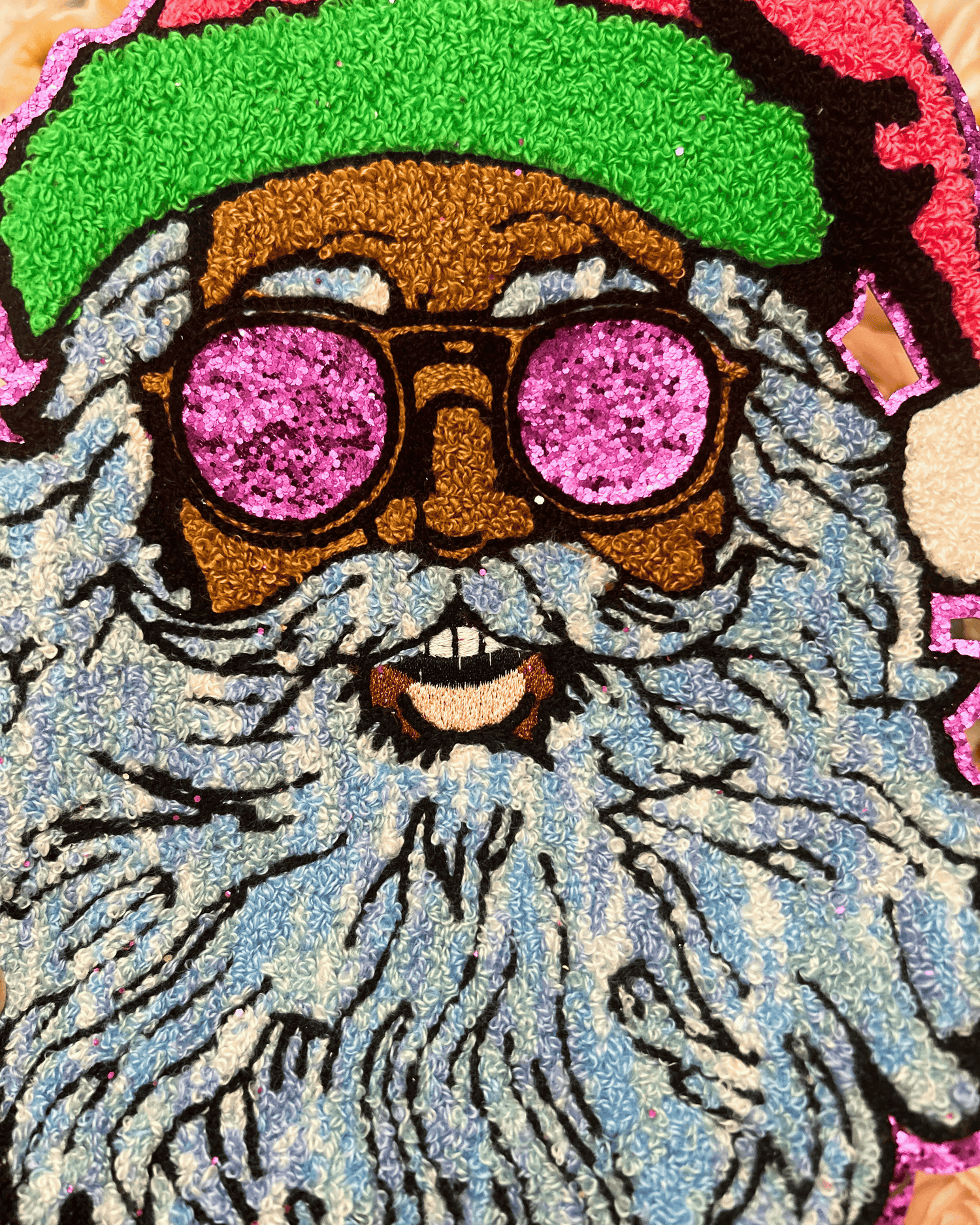 Colorful patch of a bearded character with pink sunglasses and green hat on a textured background
