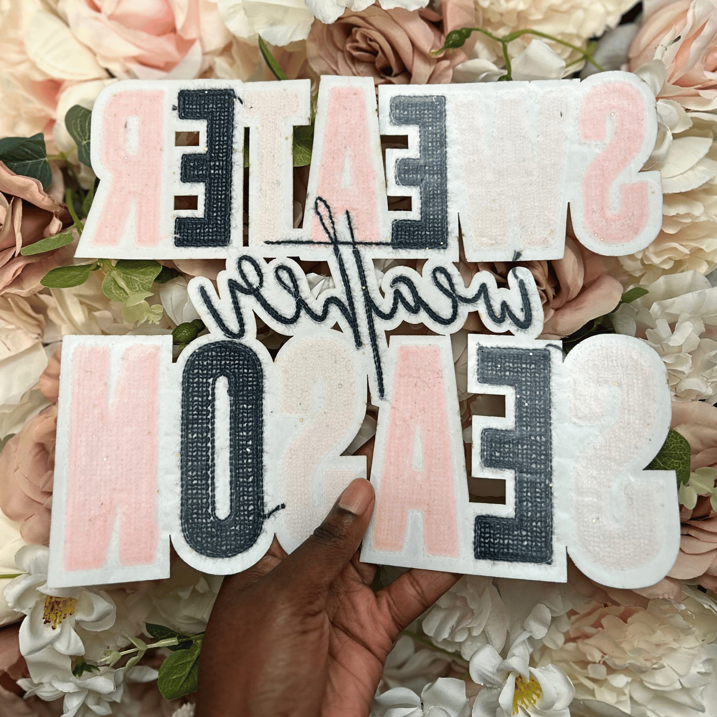 Hand holding decorative letters spelling &